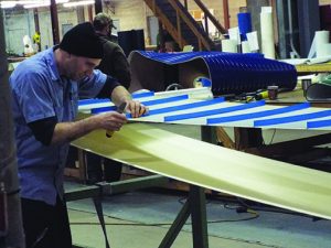 Wayne Mitchell fashions a belt with cleats that will keep products from rolling off the line.